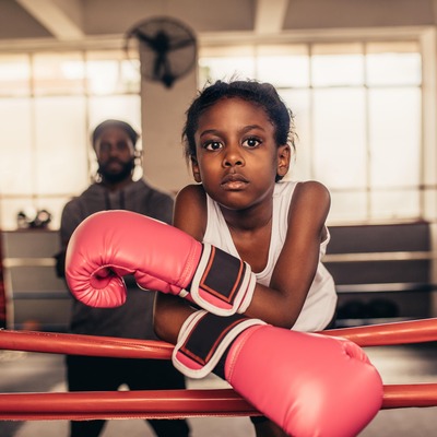 Young girl with boxing gloves on standing in a boxing ring